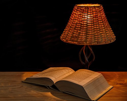 Cozy reading corner with warm desk lamp lighting on a book