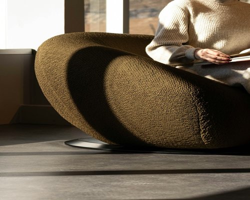 Person relaxing with closed eyes in a brightly lit comfortable room